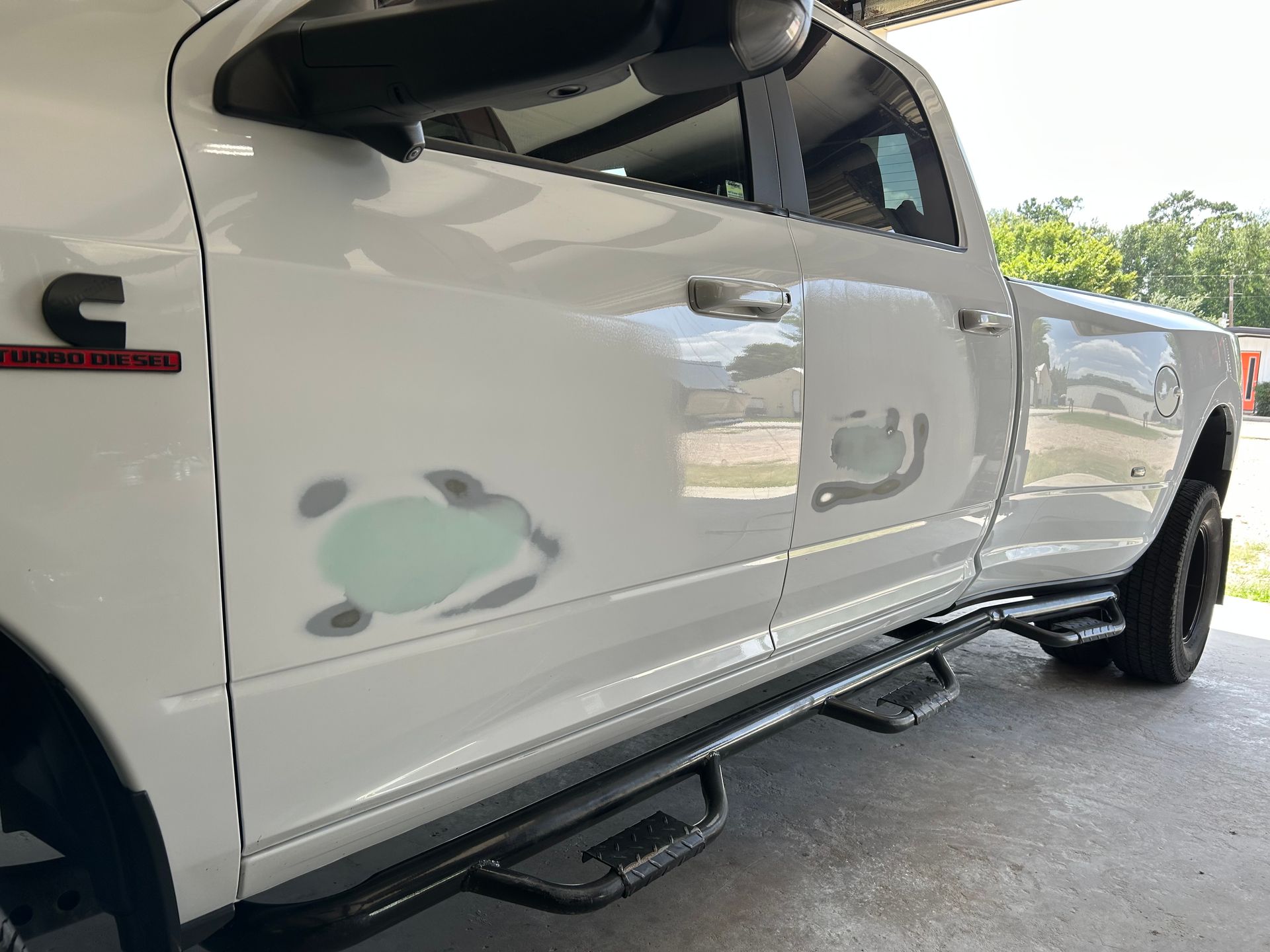 White Dodge Ram truck with body damage to the front door, side step, and Cummins logo.