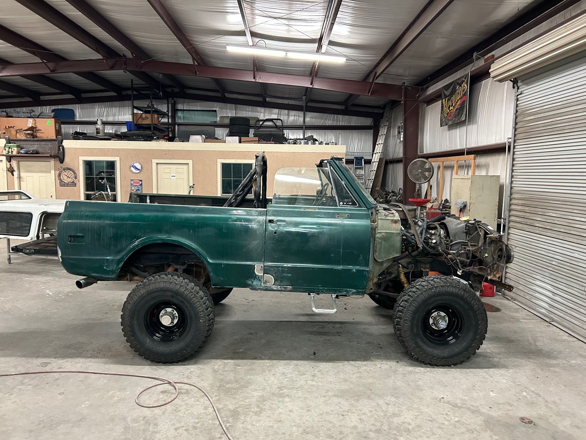 Green lifted truck frame in a garage.
