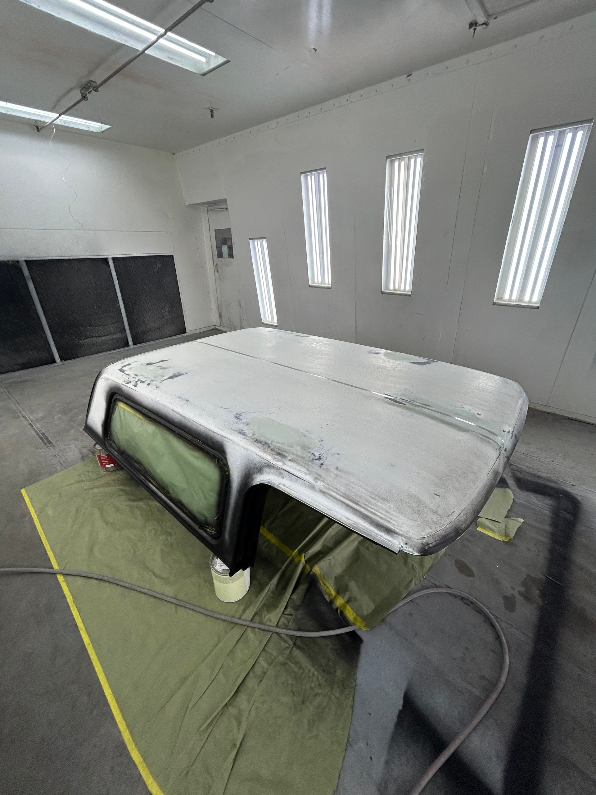 Camper shell in a paint booth, covered in primer.