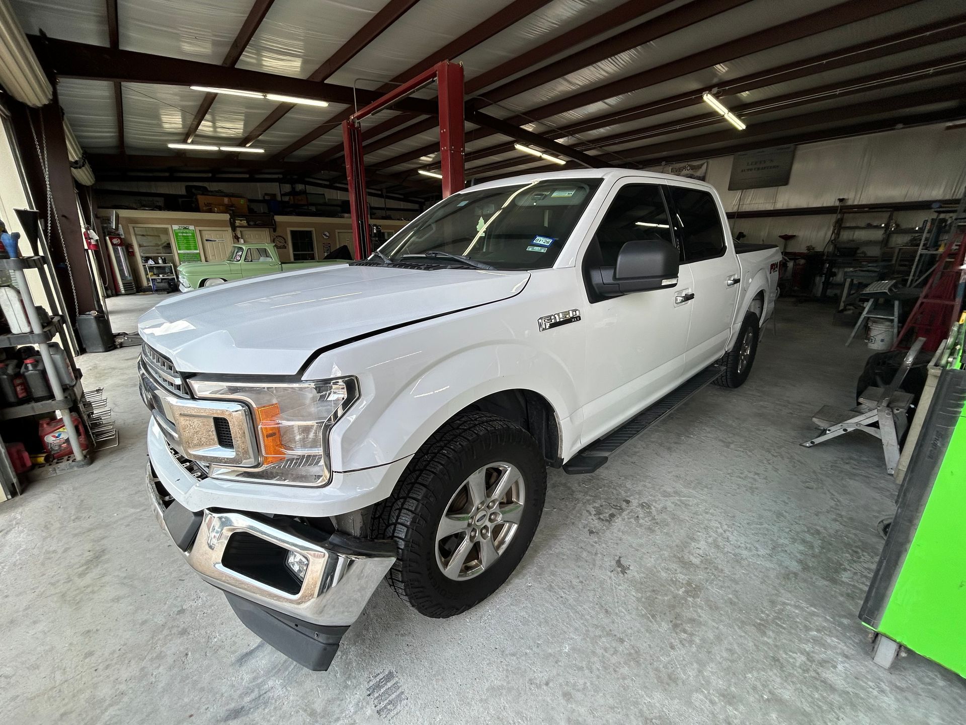 White Ford F-150 truck in a garage, parked on concrete.