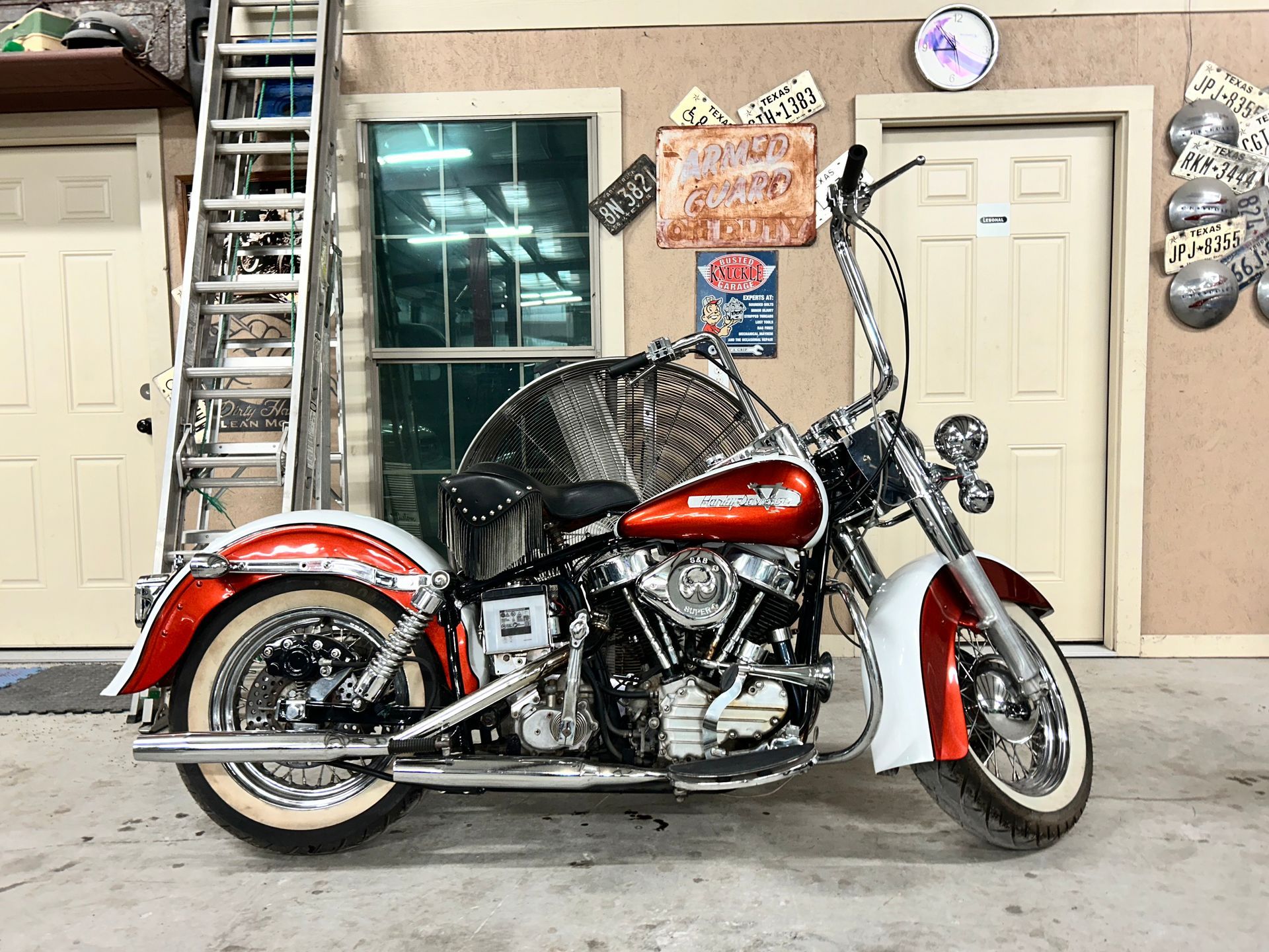 Classic red and white Harley-Davidson motorcycle with chrome accents parked in a garage setting.