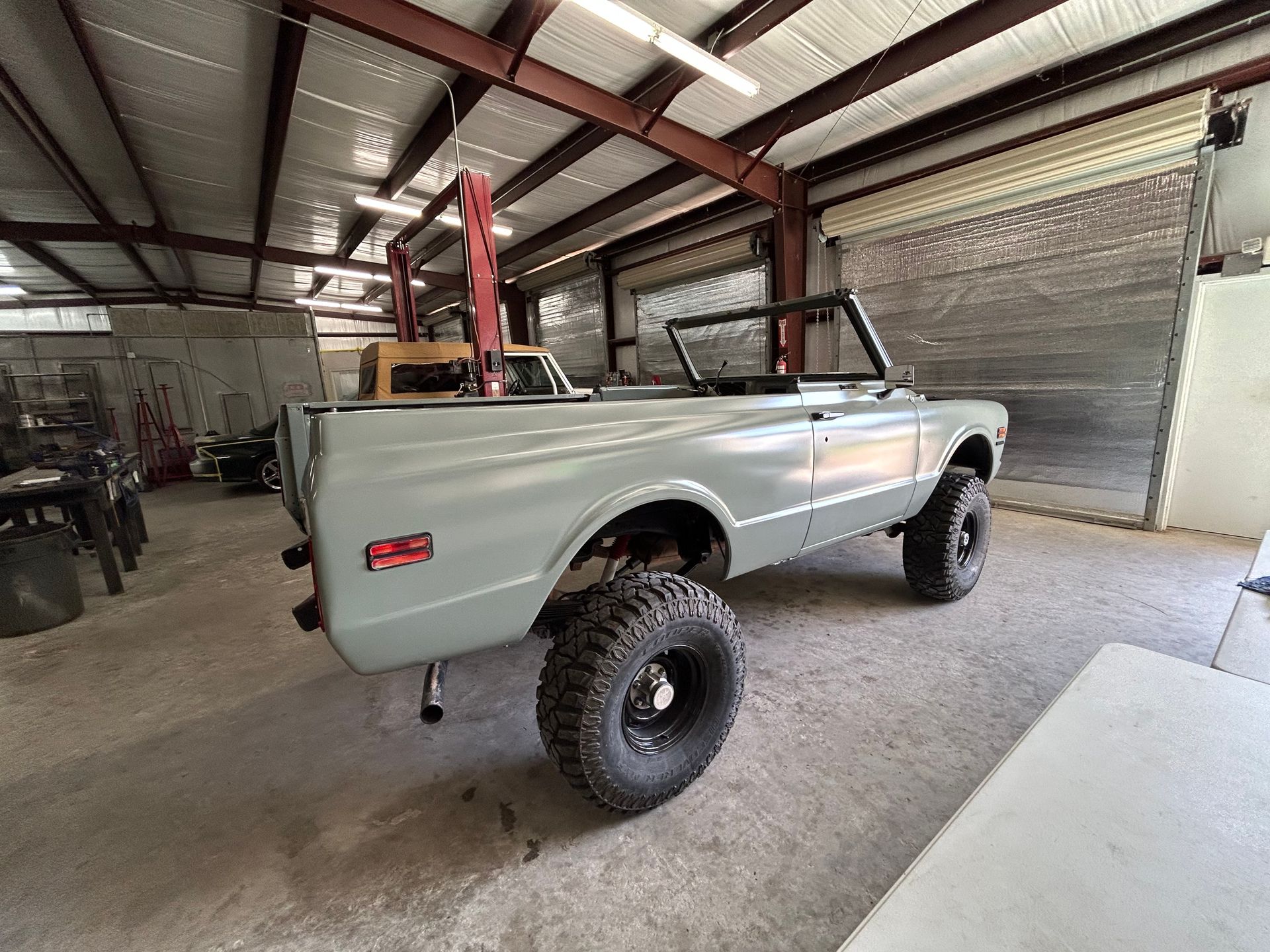 Gray, lifted, convertible Chevy Blazer in a garage.