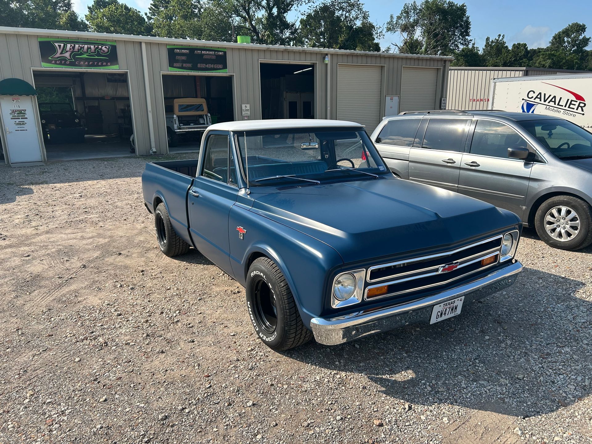 Blue classic Chevrolet pickup truck parked outside a repair shop.