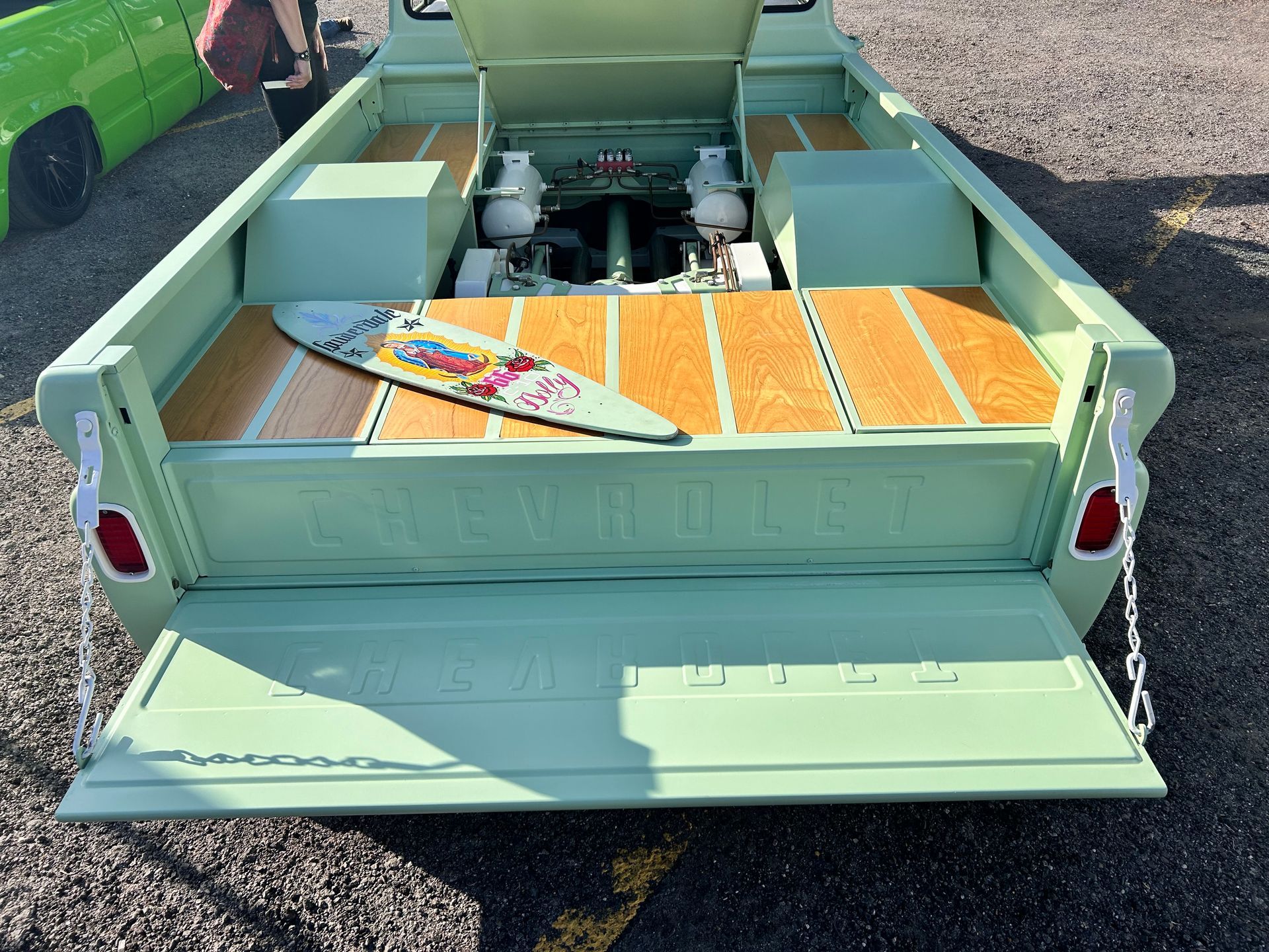 Pale green vintage truck bed with wood panels and a skateboard. Tailgate is down.