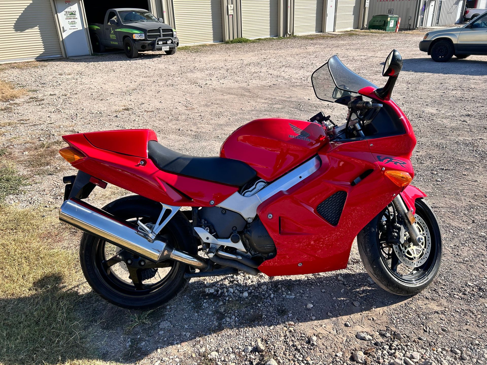 Red Honda VFR motorcycle parked on gravel.