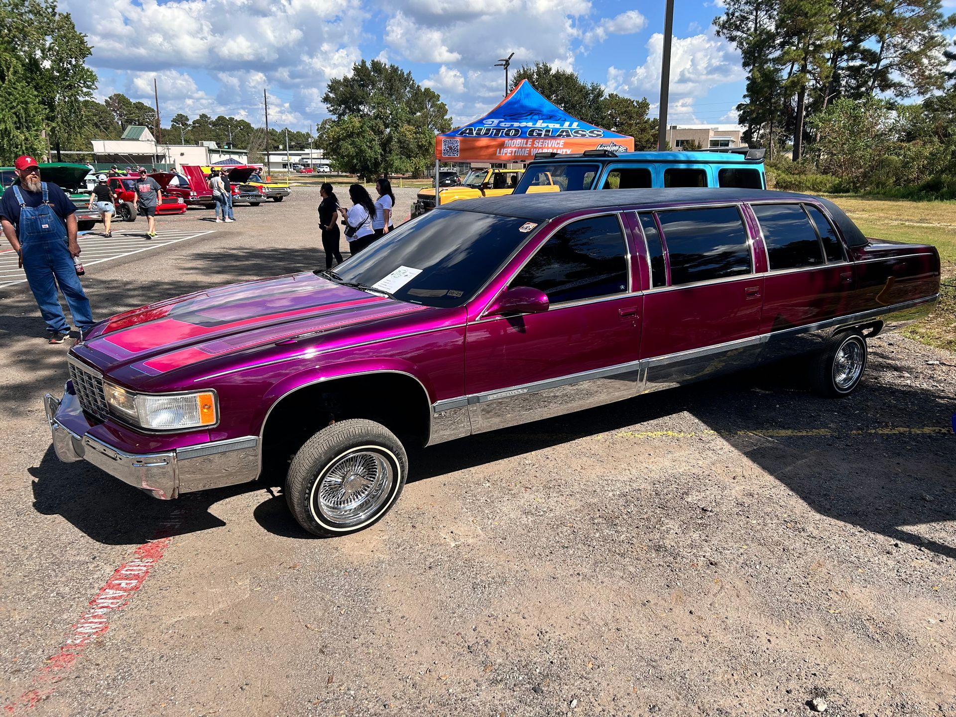 Purple limousine with chrome accents at an outdoor car show.