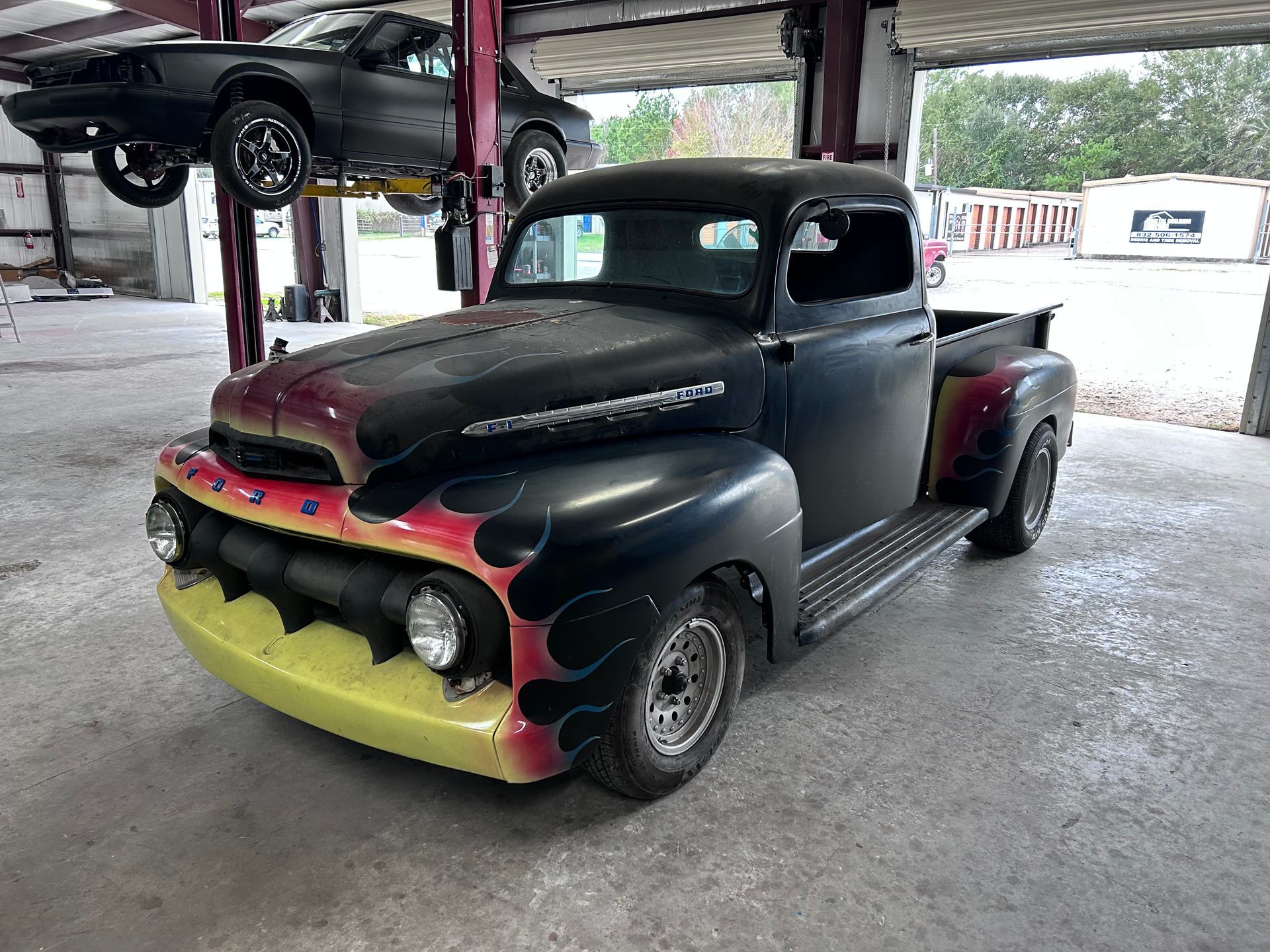 Black Ford truck with flame decals in a garage.