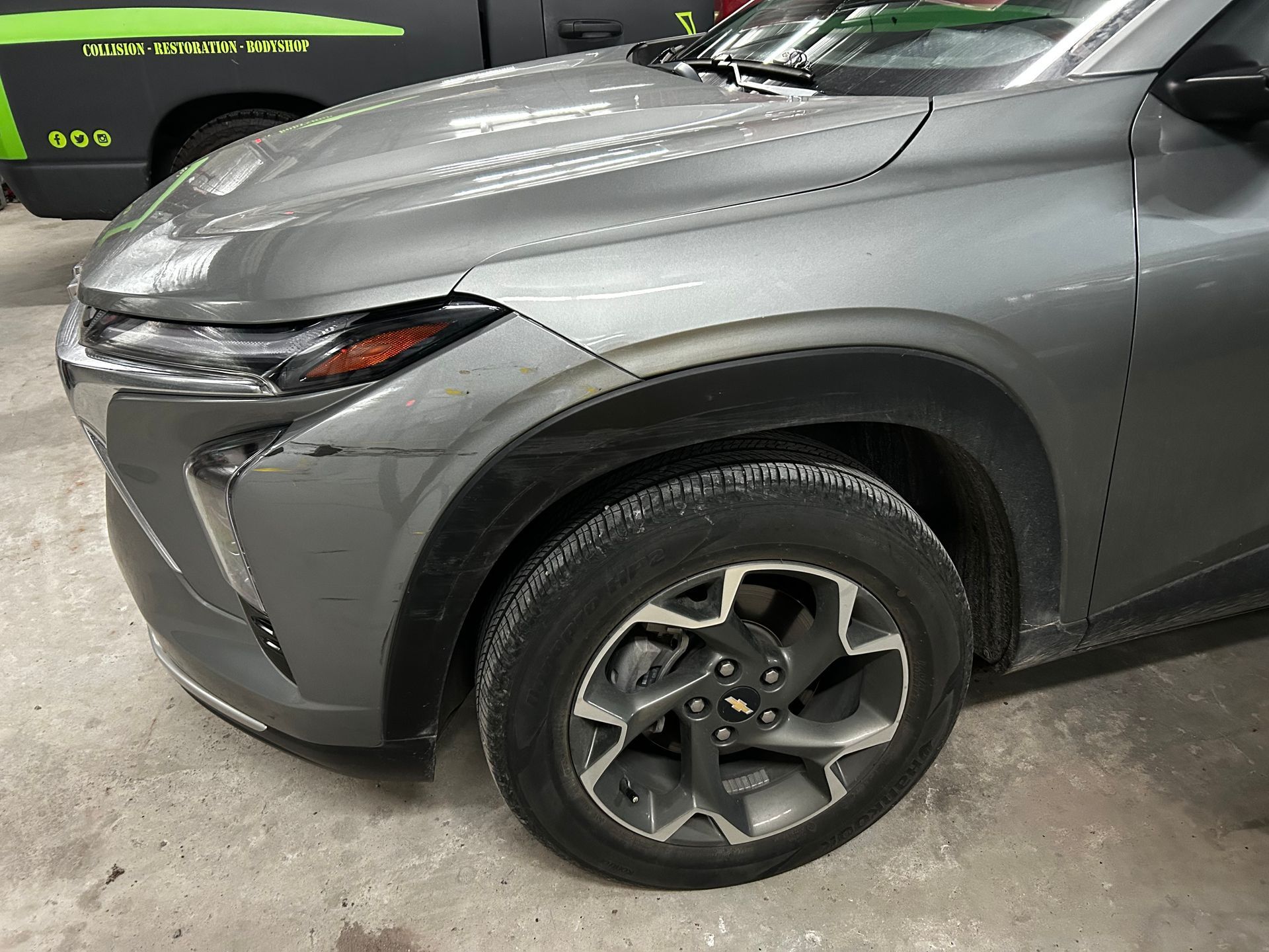 Gray Chevrolet SUV, front view, with black fender.  The vehicle is parked indoors.