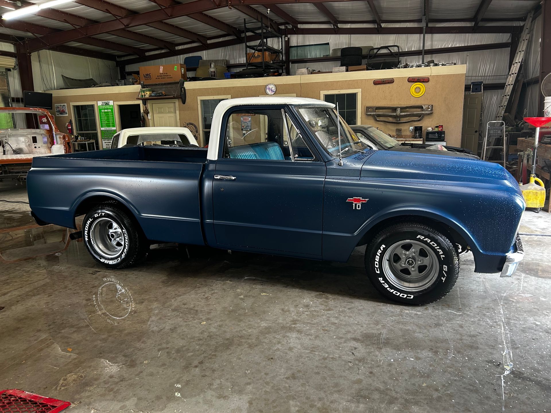 Blue and white vintage pickup truck in a garage.