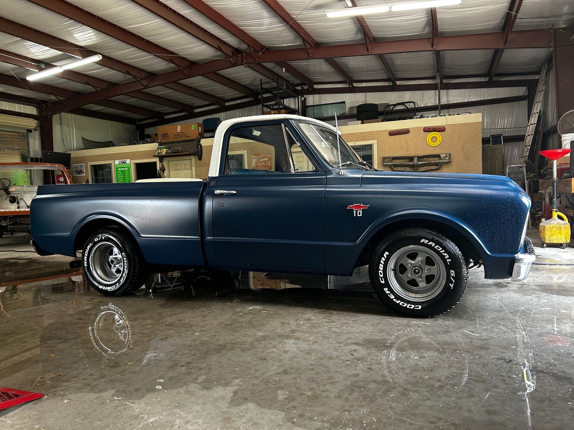 Blue Chevrolet pickup truck with white top parked inside a garage.