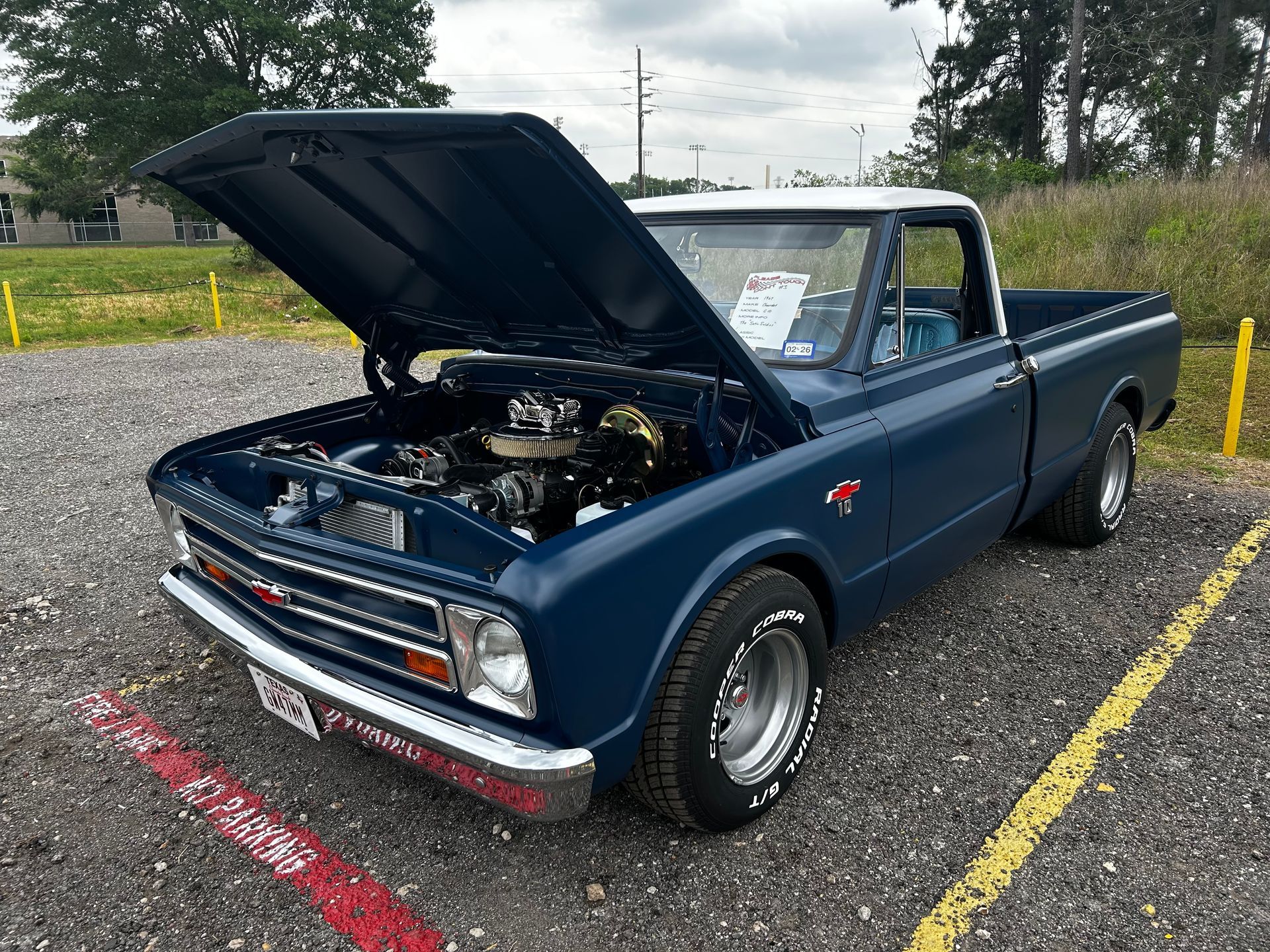 Blue classic Chevrolet pickup truck, hood open, parked on gravel.