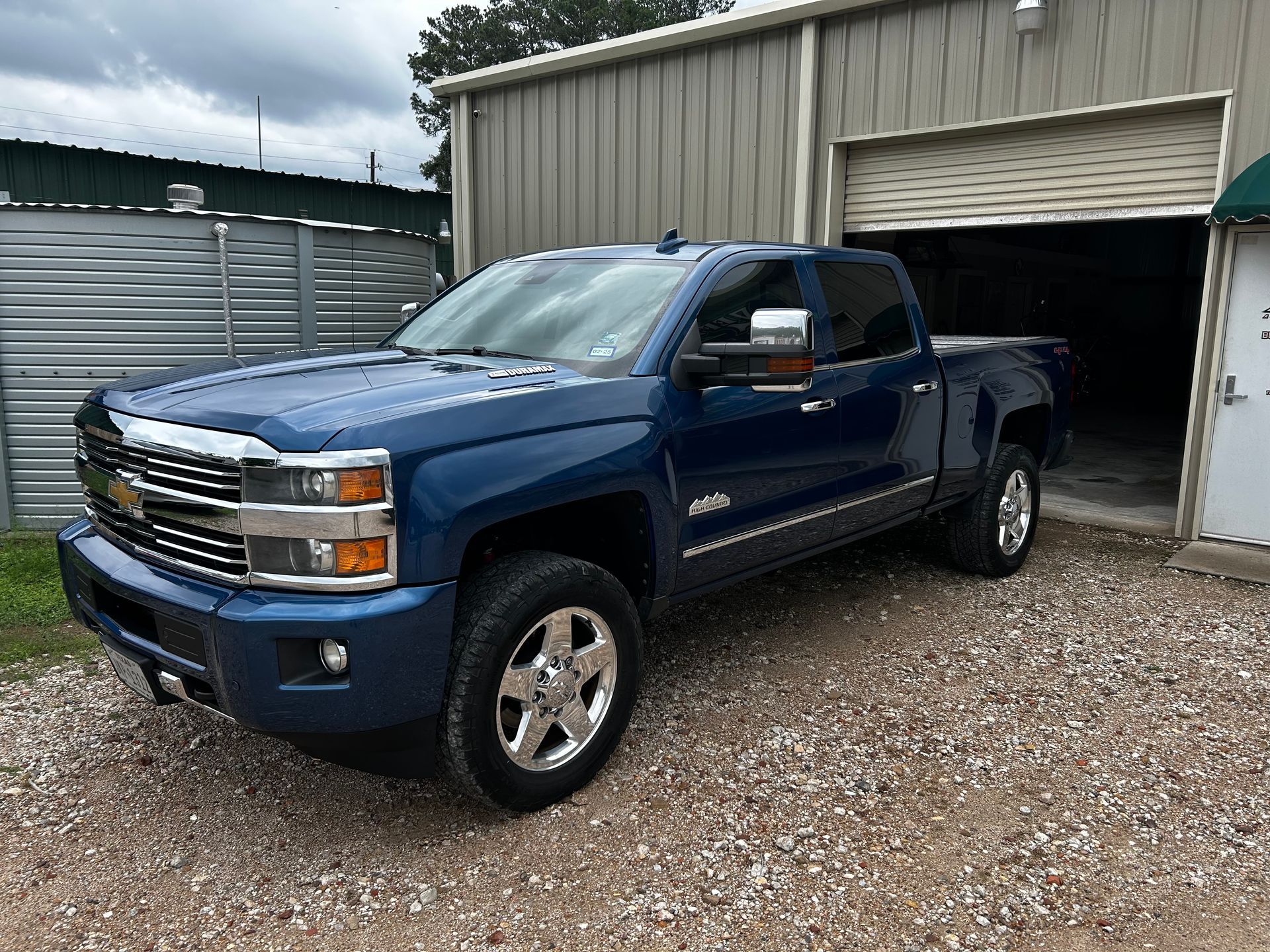 Blue Chevy truck parked outside a building with a metal door.