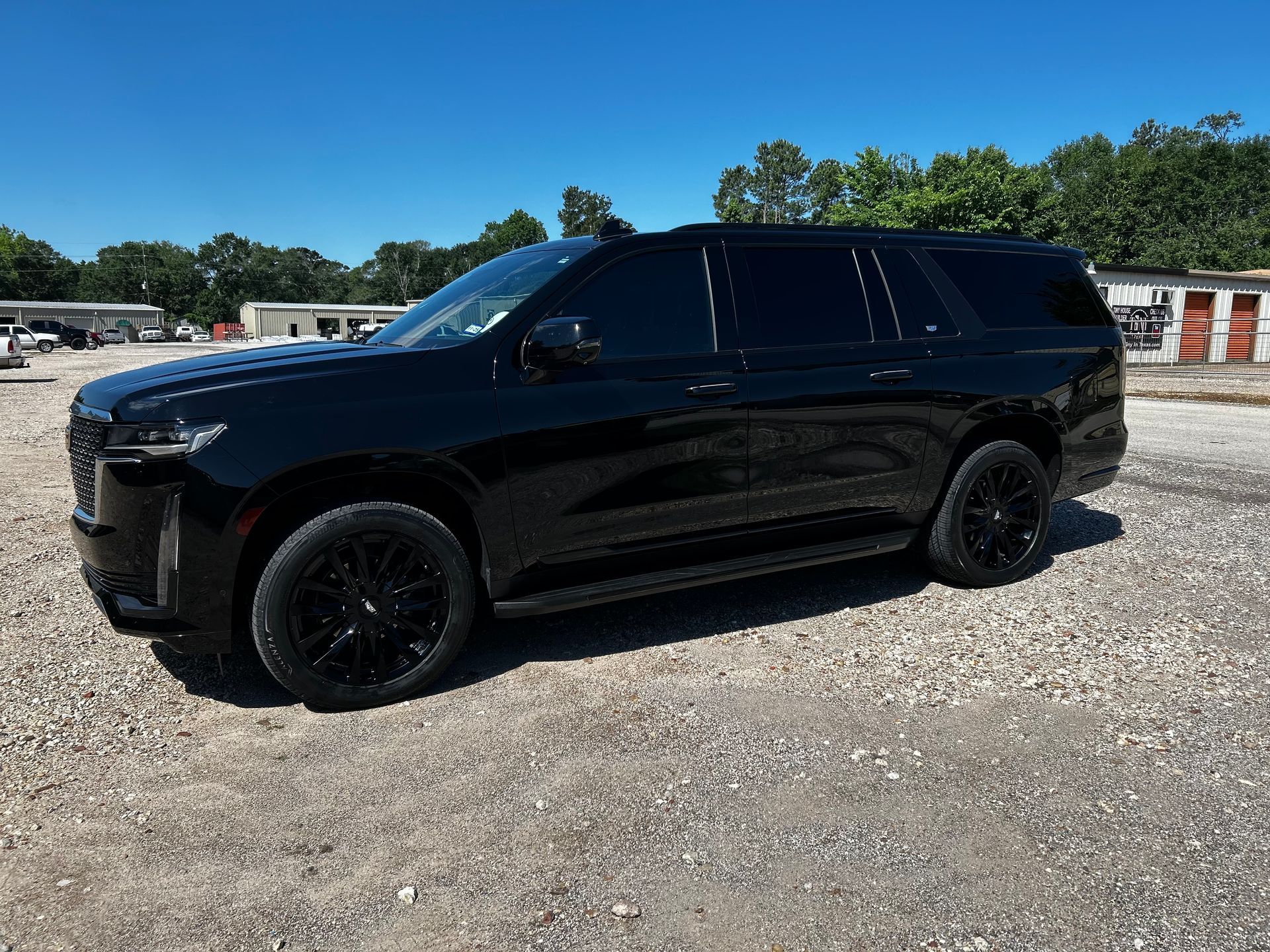 Black SUV parked on gravel lot under a blue sky.