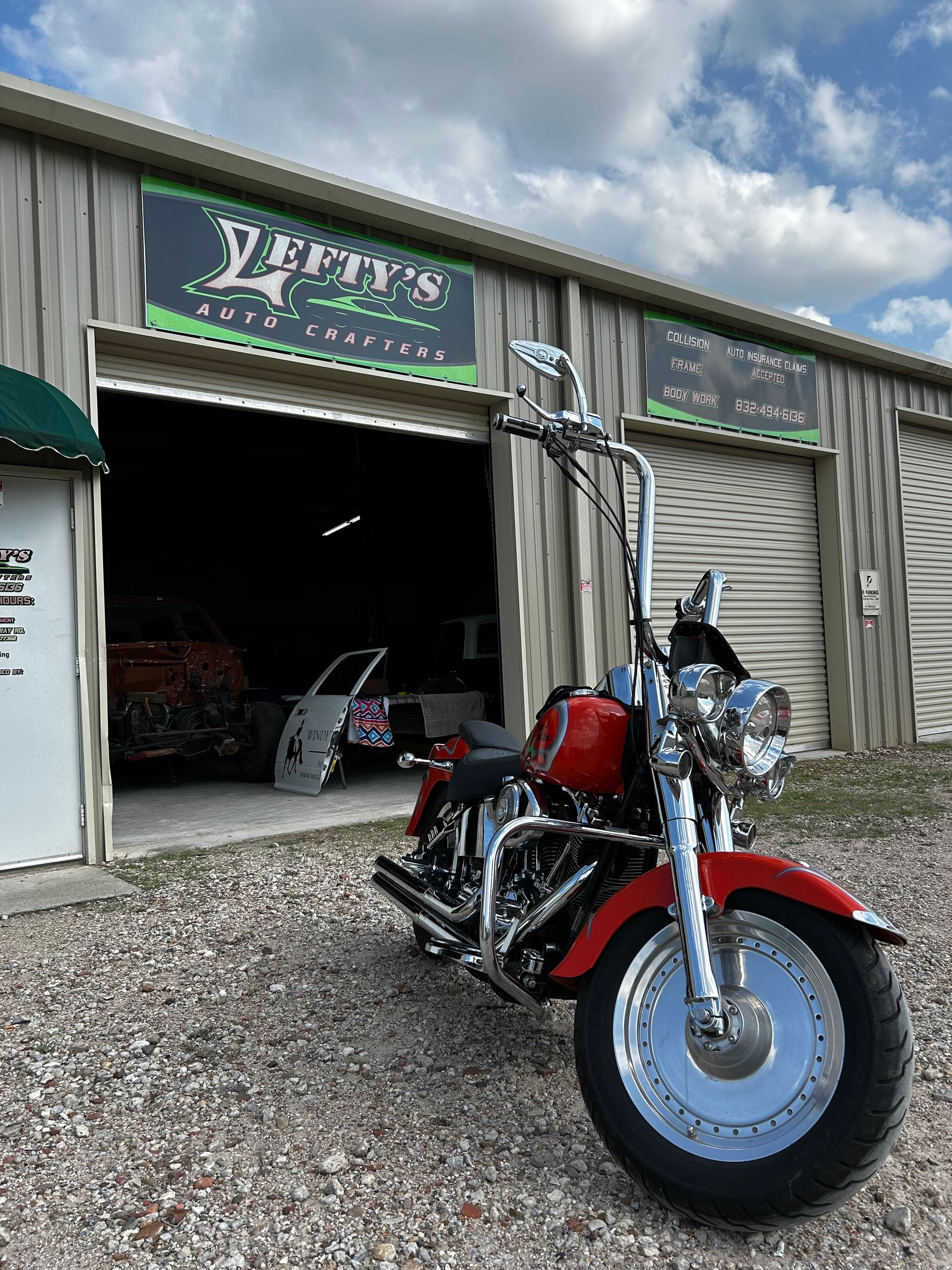 Red motorcycle parked in front of a garage with a sign that reads 