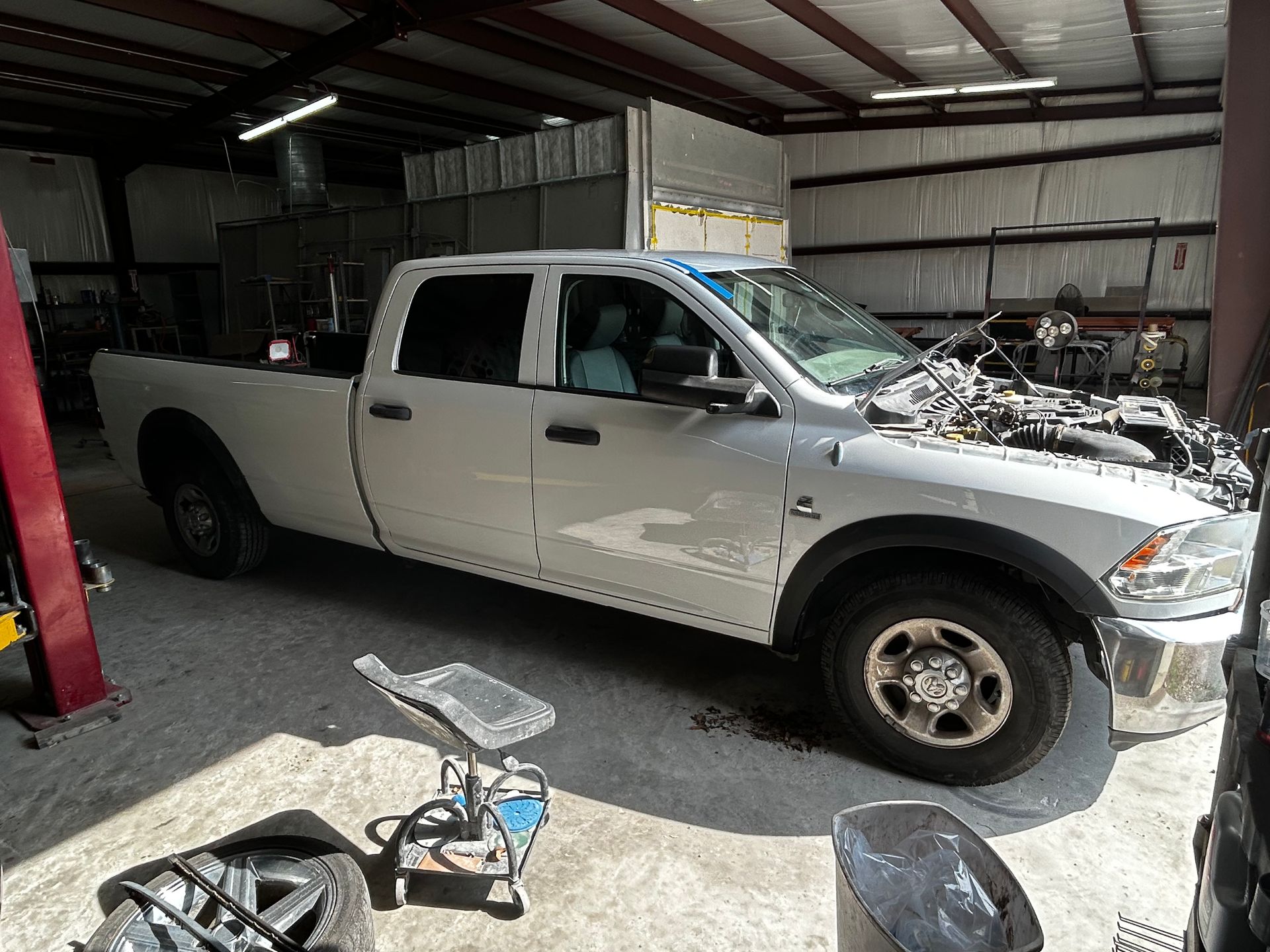 White Ram pickup truck inside a garage with the hood open.