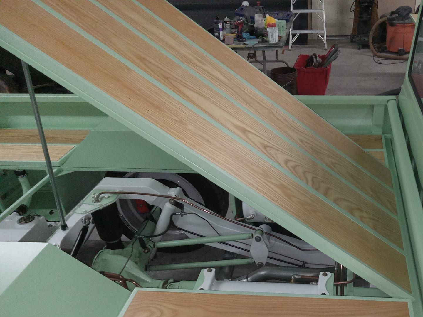 Light green truck bed with wooden planks, angled open.