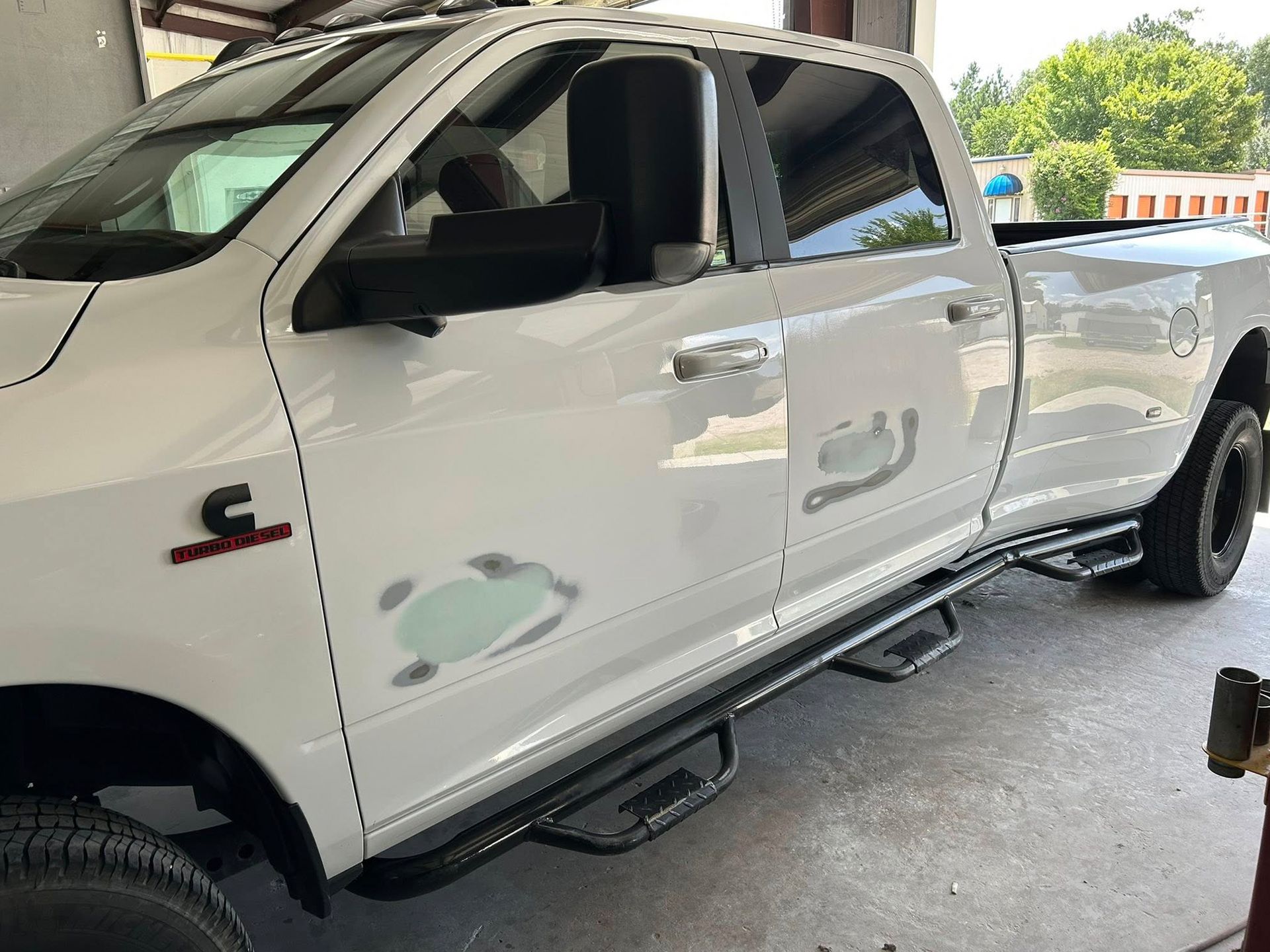White Ram pickup truck with visible bodywork in a repair shop.