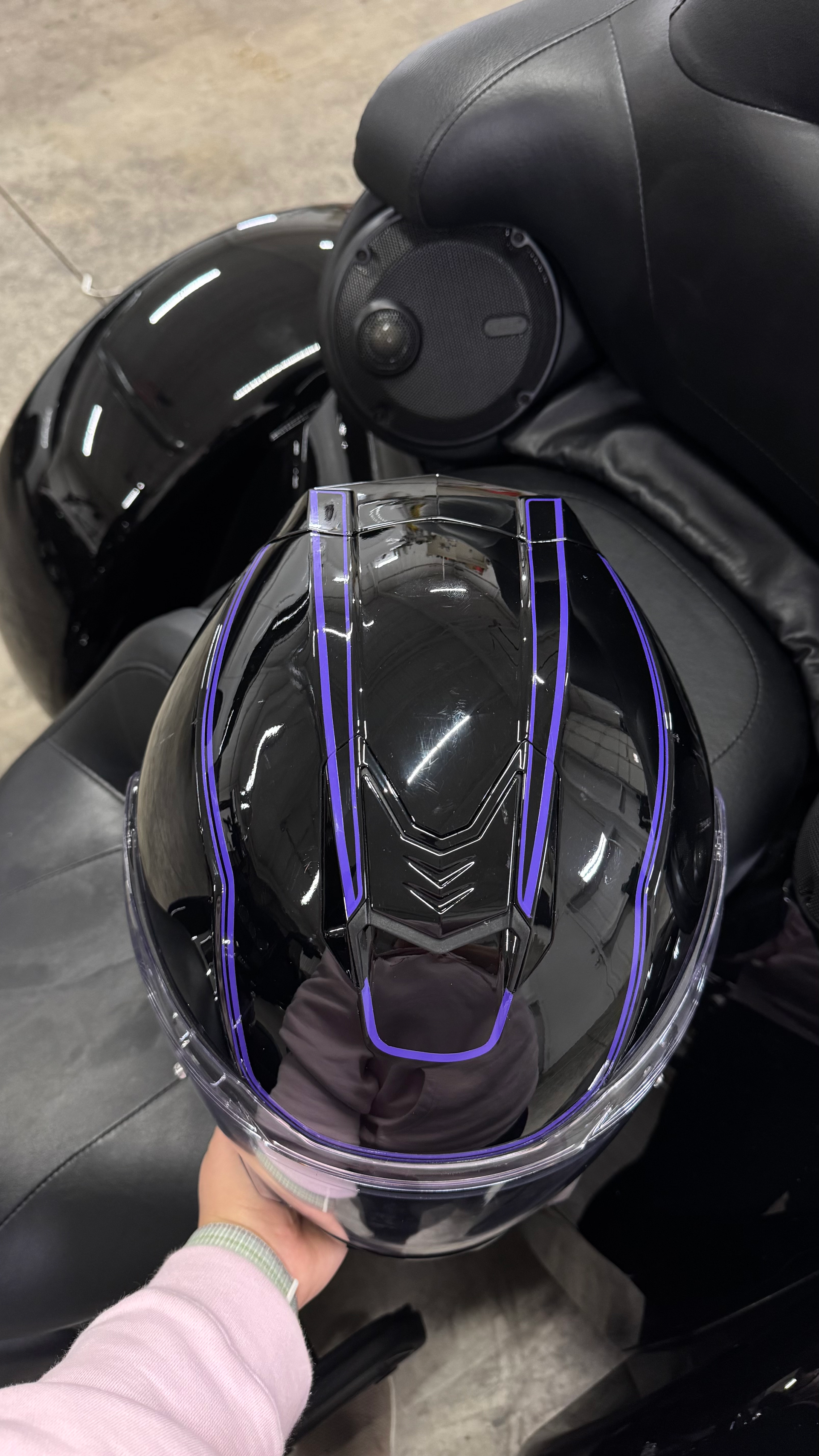 Black motorcycle helmet with purple accents, held in hand.