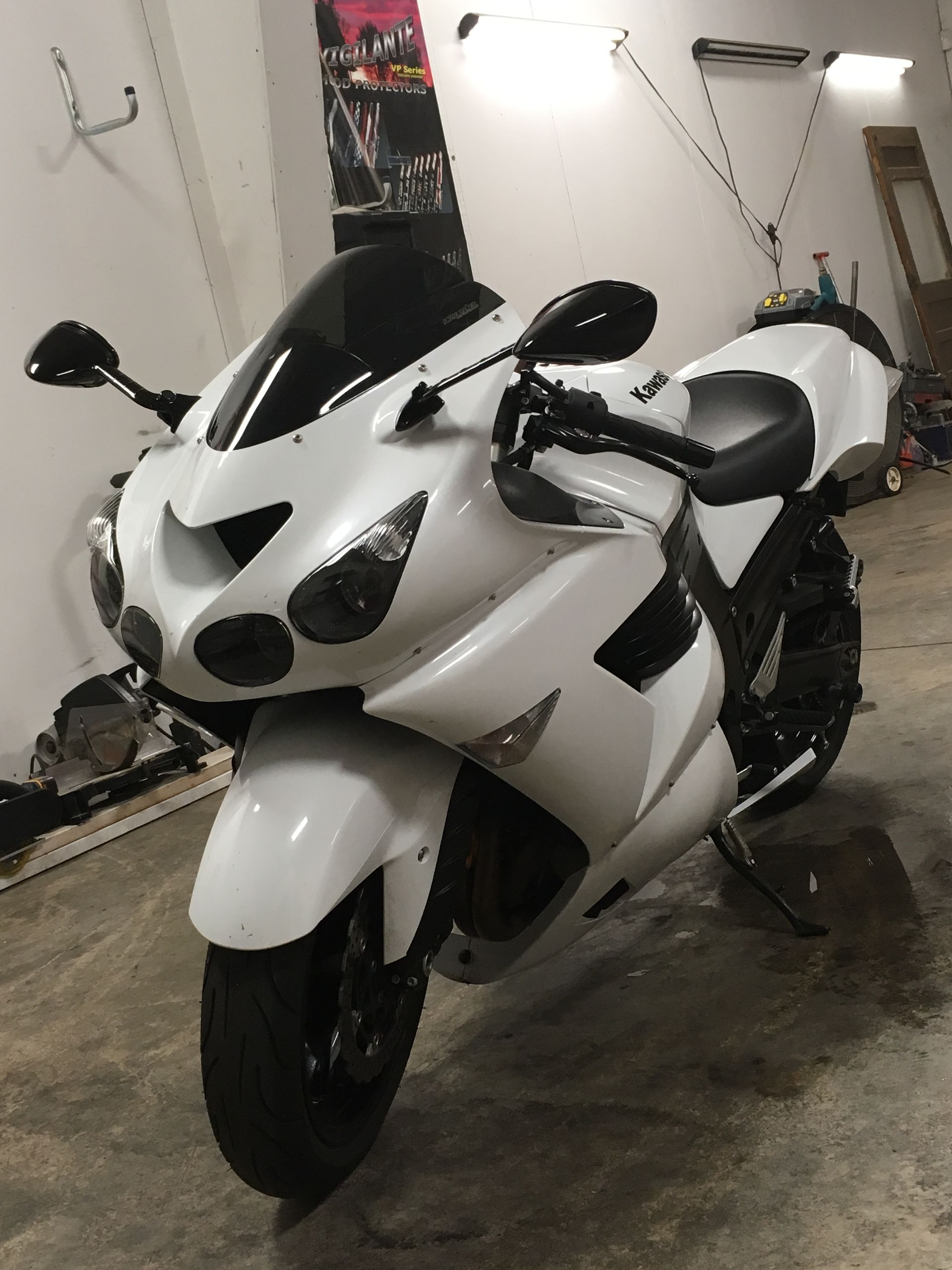 White sport motorcycle parked in a garage. Black windscreen, tires, and accents.