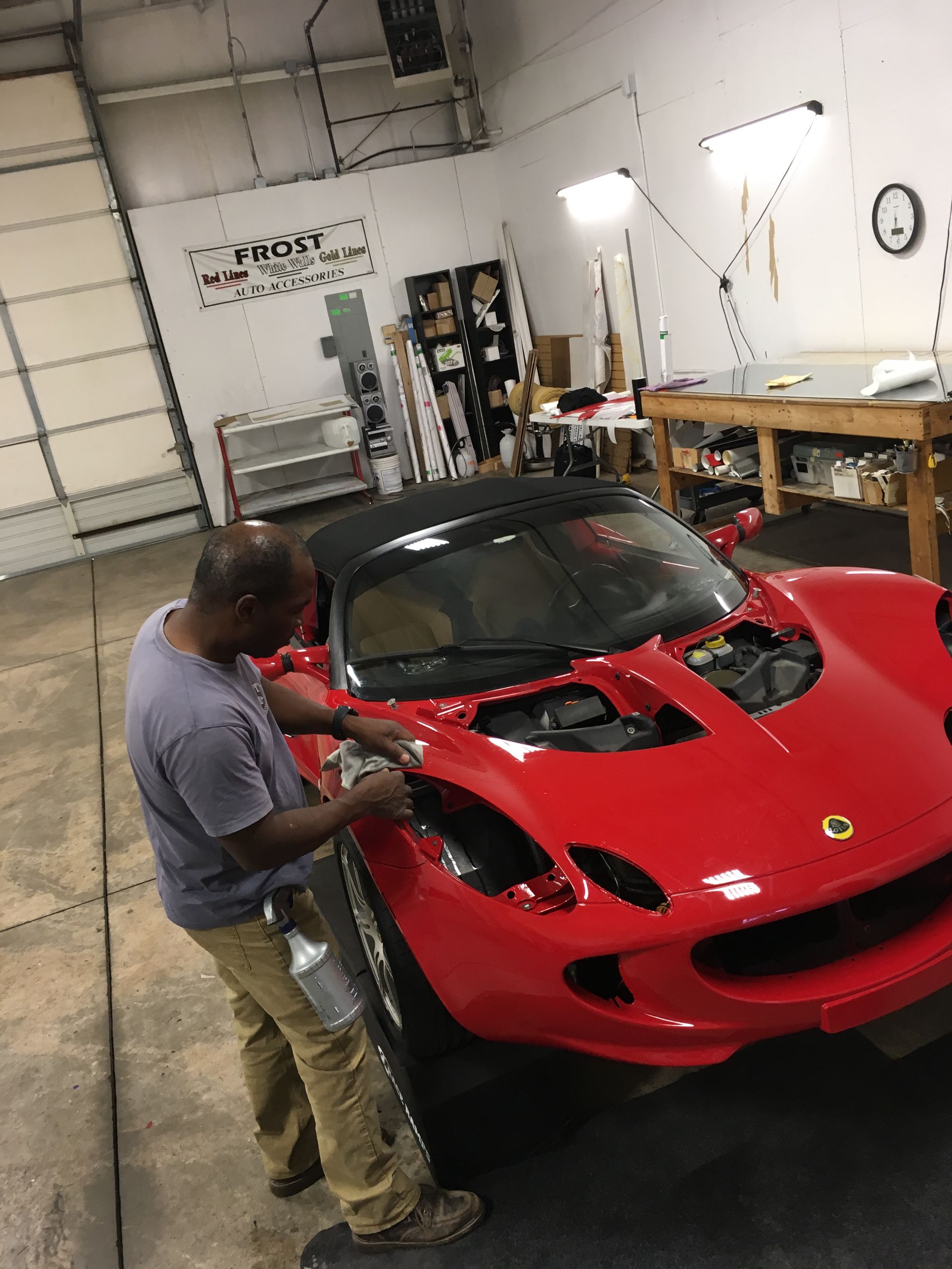 Man working on a red Lotus sports car in a garage.