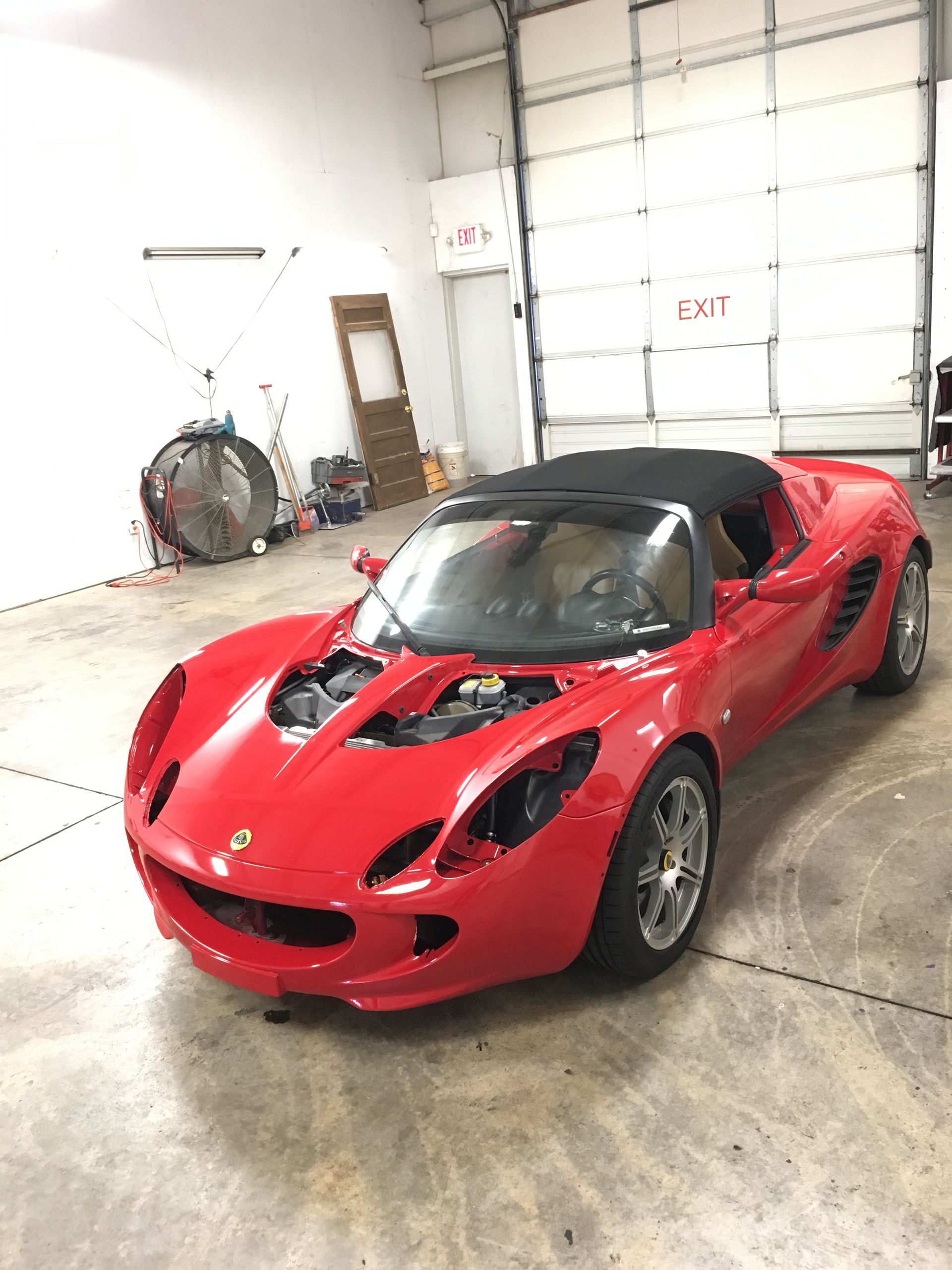 Red Lotus Elise convertible car in a garage.