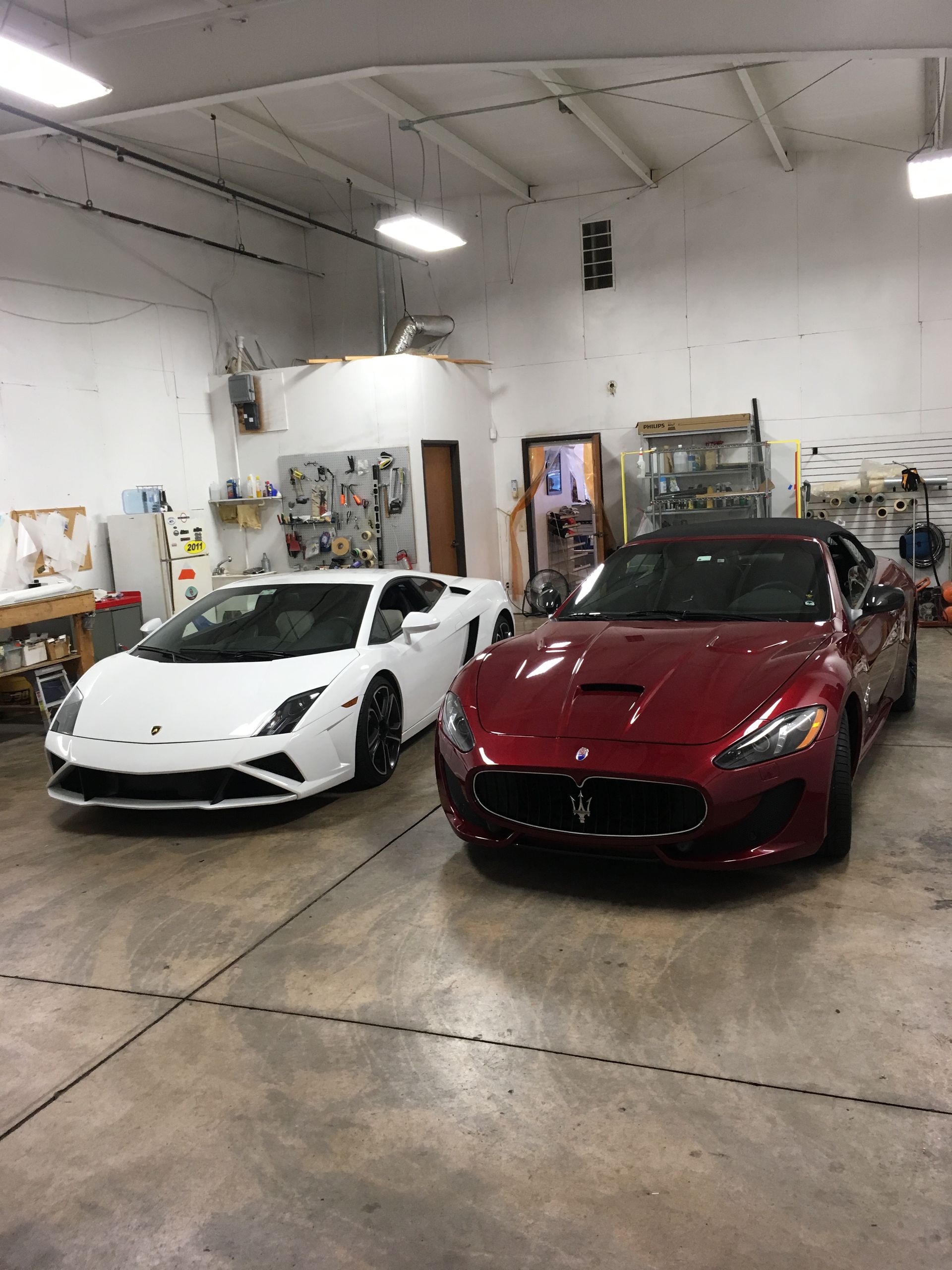 A white Lamborghini and a red Maserati inside a garage.