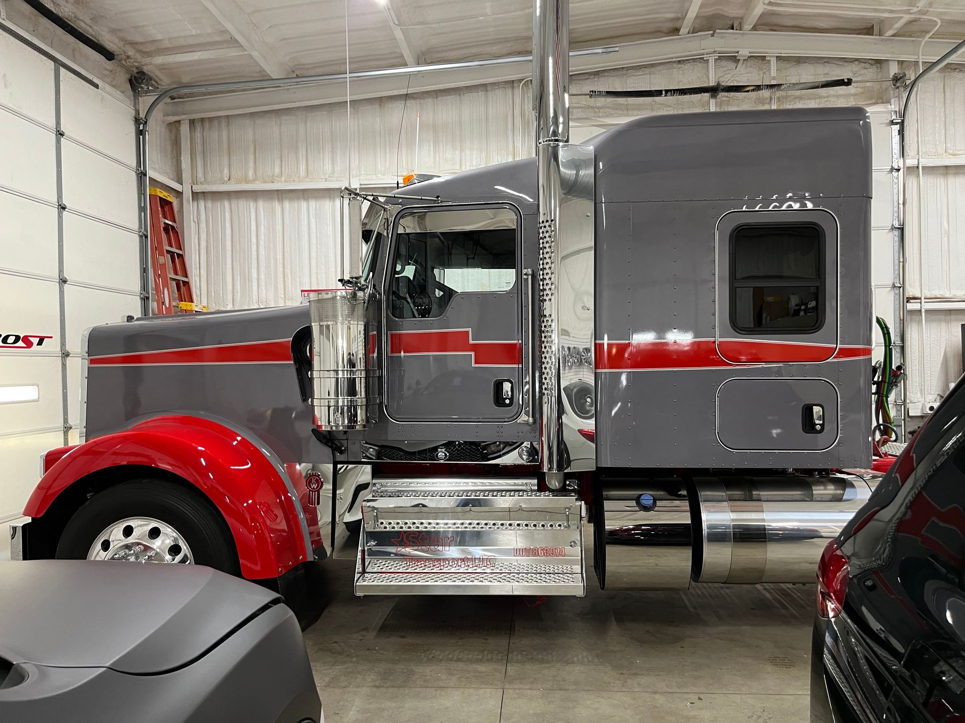 Gray and red semi-truck inside a garage. The truck has chrome accents and red fenders.