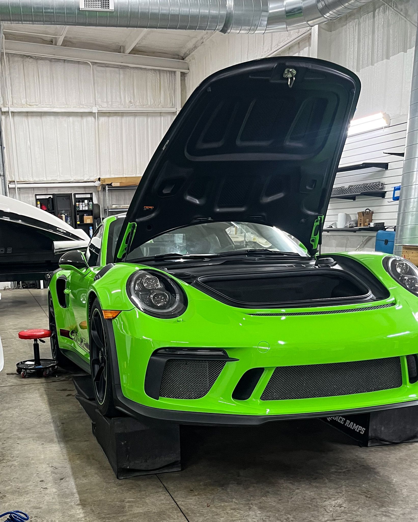 Bright green Porsche with open hood in a garage.