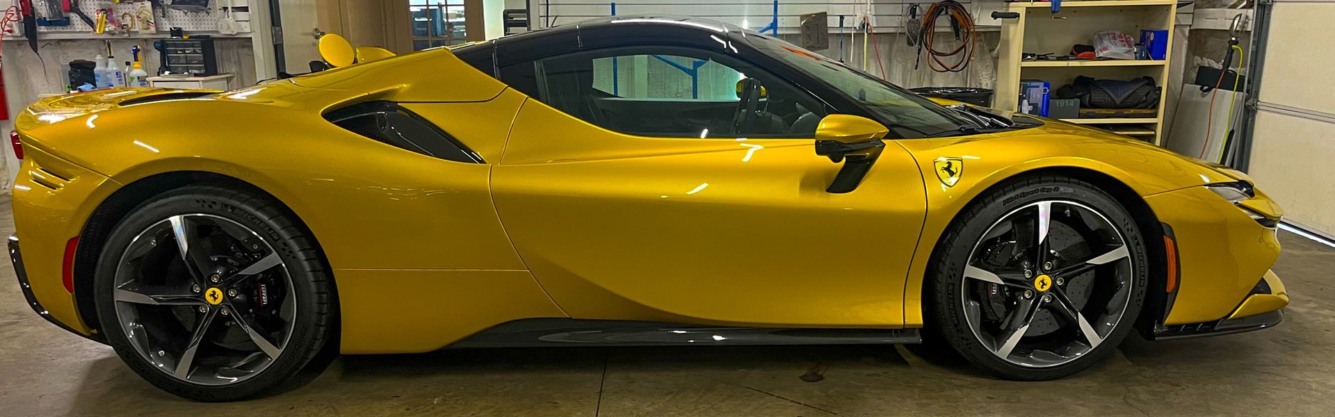Yellow Ferrari SF90 sports car parked inside a garage.