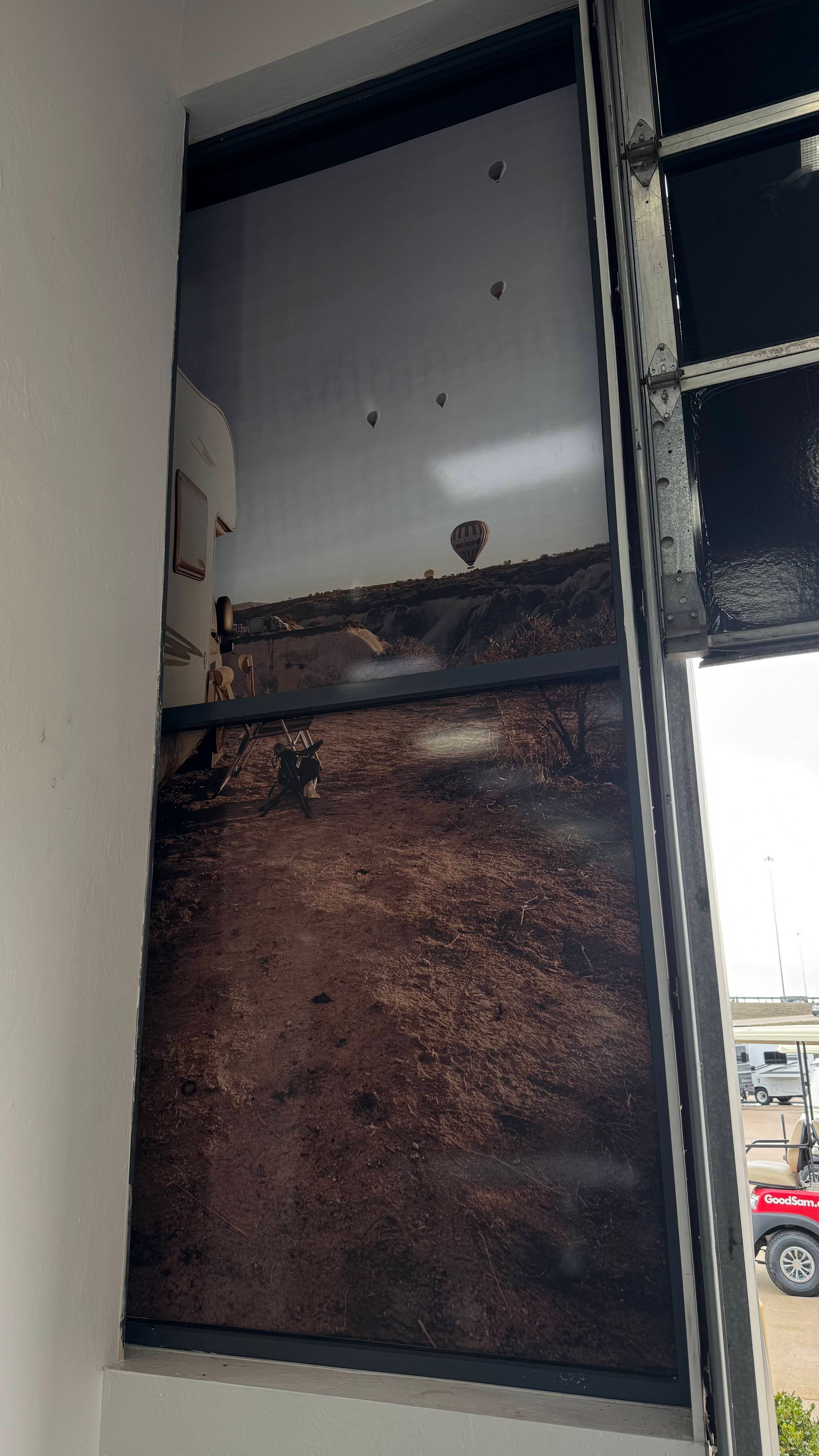 A dark and dirty open window with a black frame, showing a view to the outdoors.