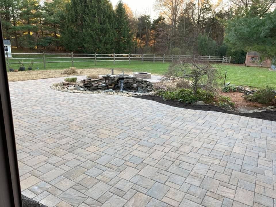 A patio with a fountain in the middle of it and a fence in the background.