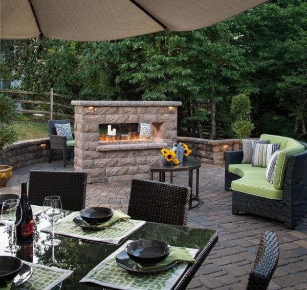 A patio with a table and chairs and a fireplace