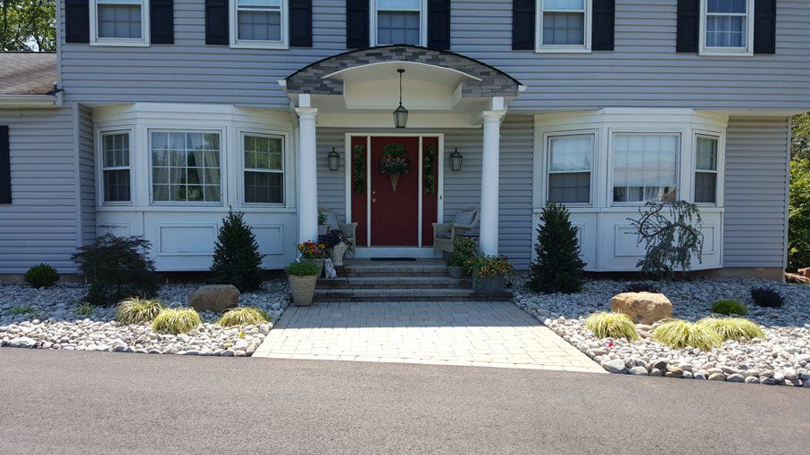 A grey house with a red door and black shutters