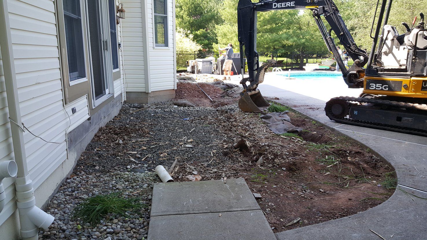 A yellow excavator is digging in front of a house