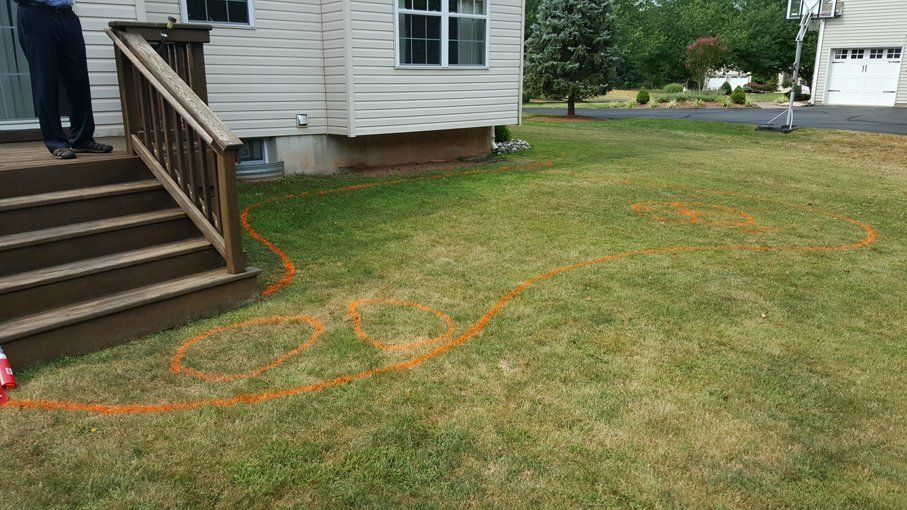 A man is standing in front of a house with a circle drawn in the grass.