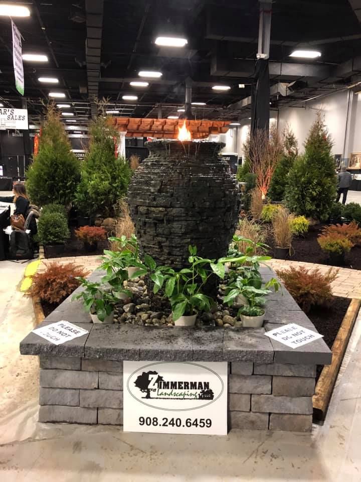 A large vase is sitting on top of a brick base in a garden.