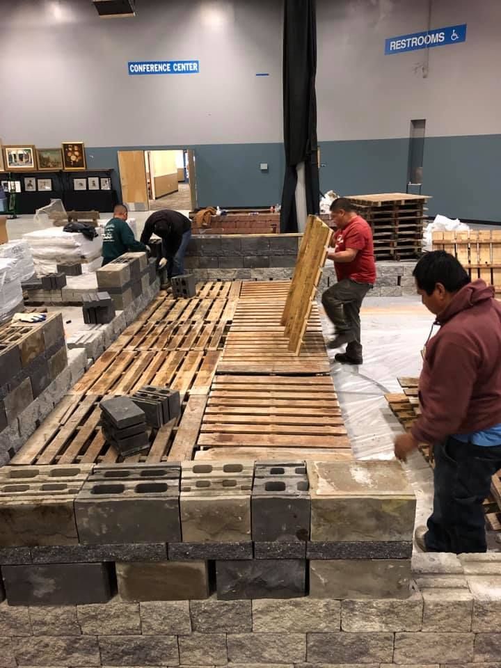 A group of men are working on a brick wall in a building.