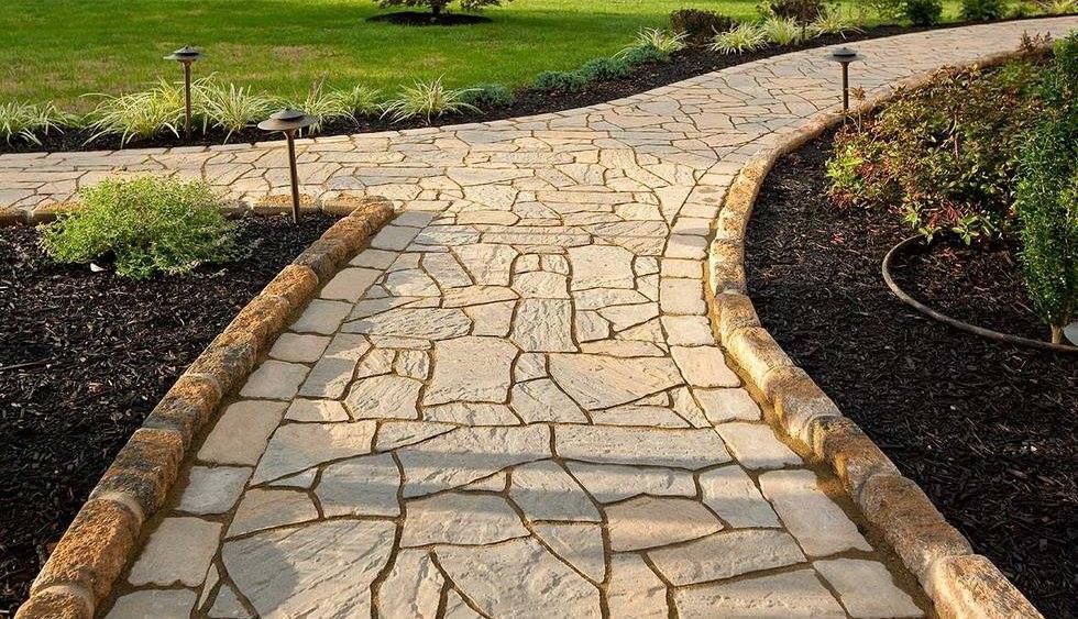 A stone walkway going through a lush green garden