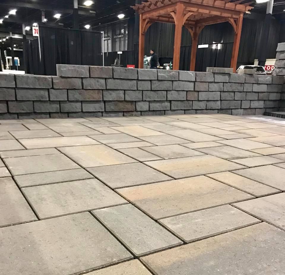 A brick wall with a wooden pergola in the background