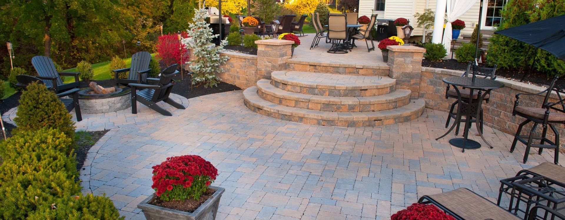 A patio with chairs , tables , and stairs in front of a house.