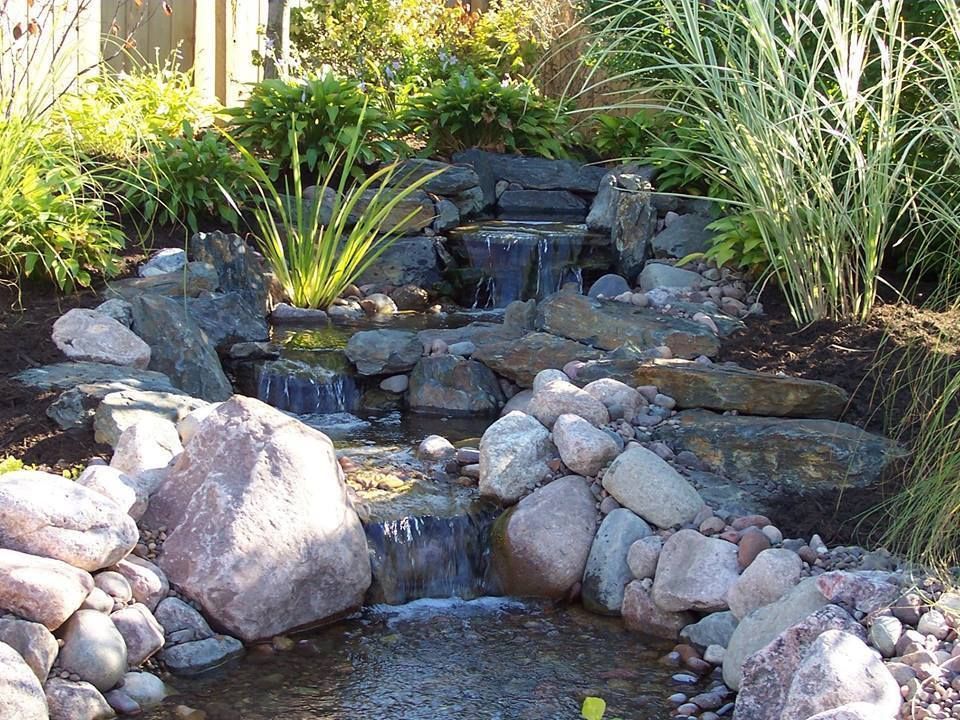 A waterfall is surrounded by rocks and plants in a garden.