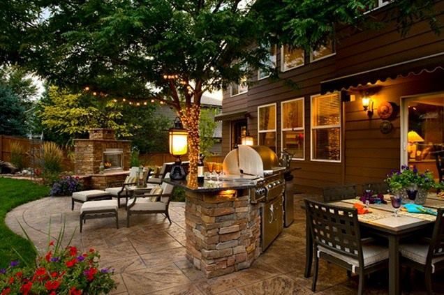 A patio with a table and chairs and a kitchen in the backyard.