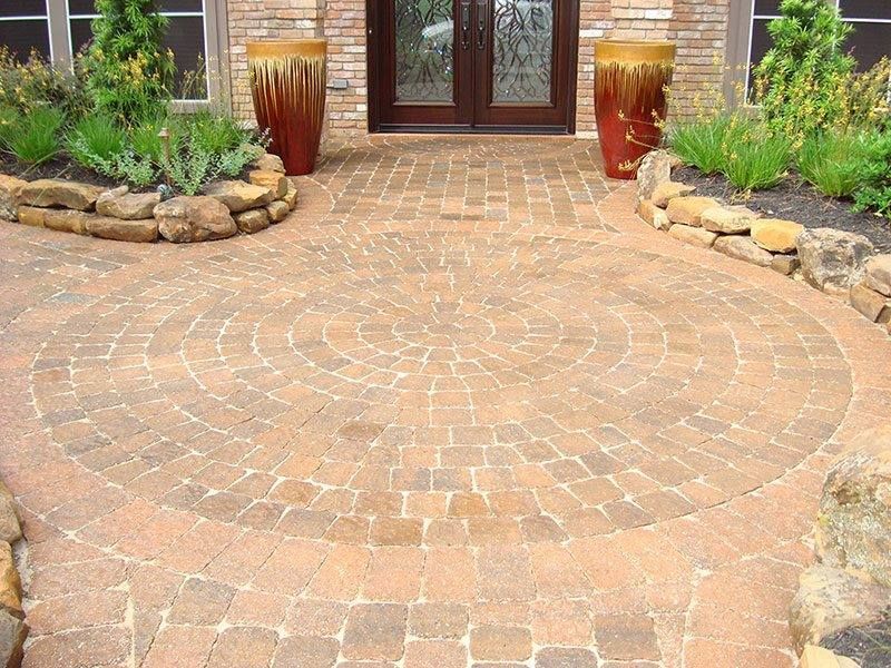A circular brick walkway in front of a brick house