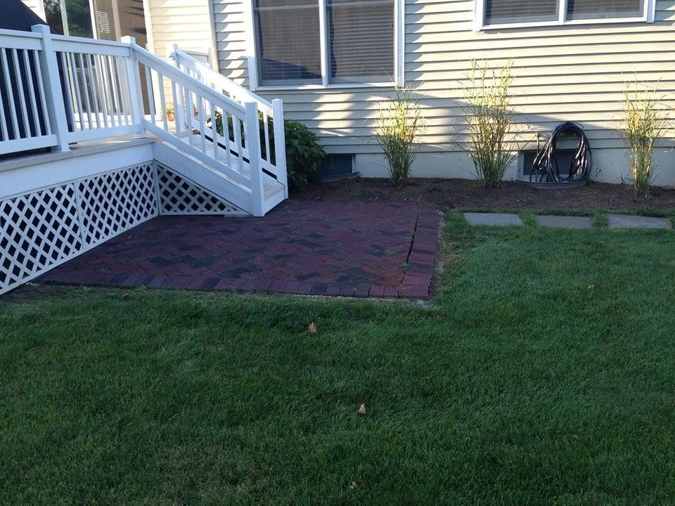 A backyard with a brick walkway and a white railing