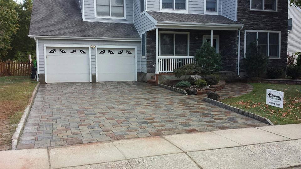 A house with two garage doors and a brick driveway
