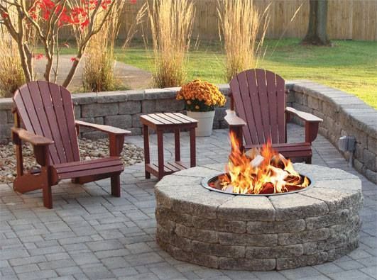 A fire pit on a patio with two chairs and a table.