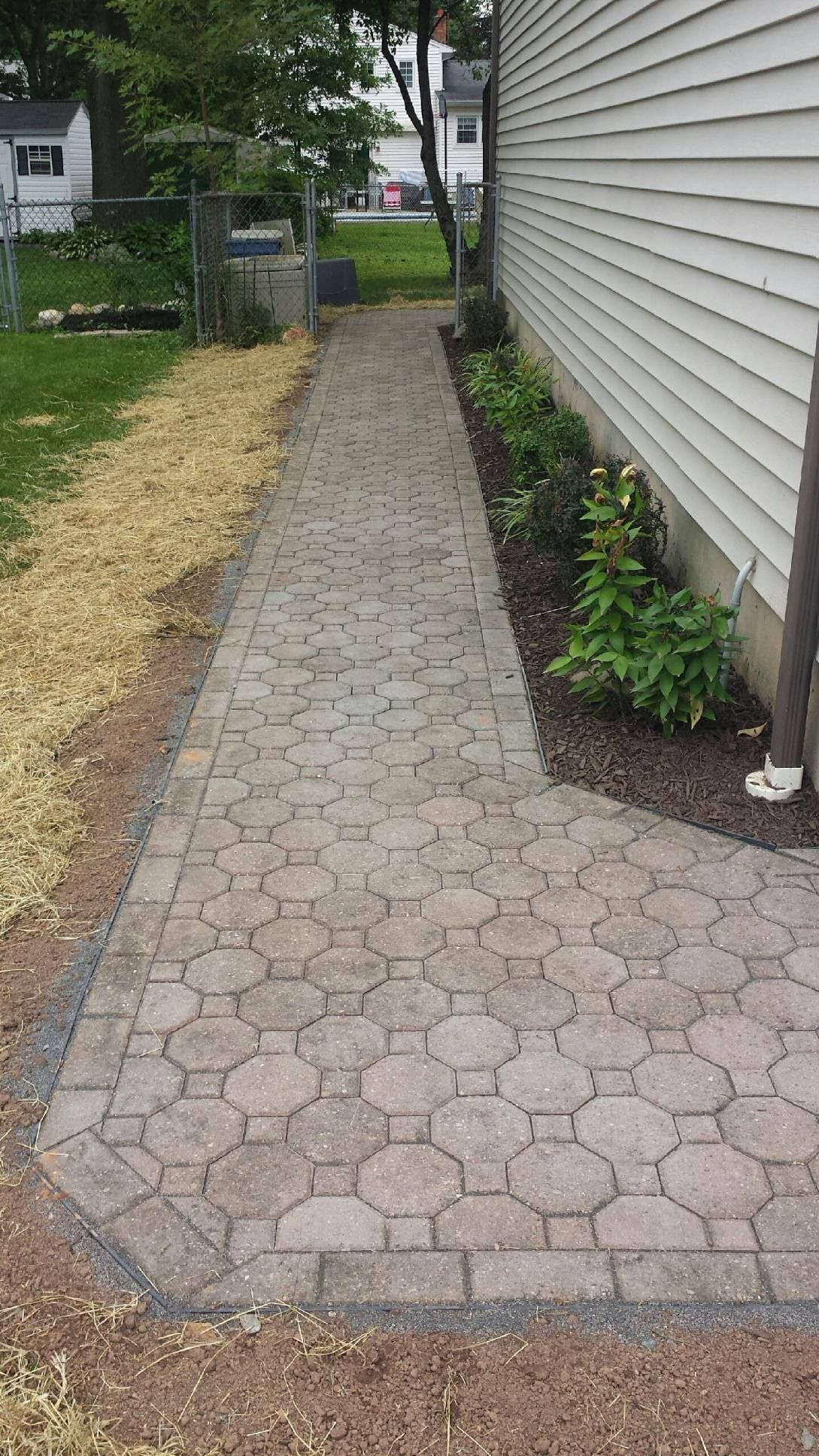 A brick walkway leading to the side of a house.