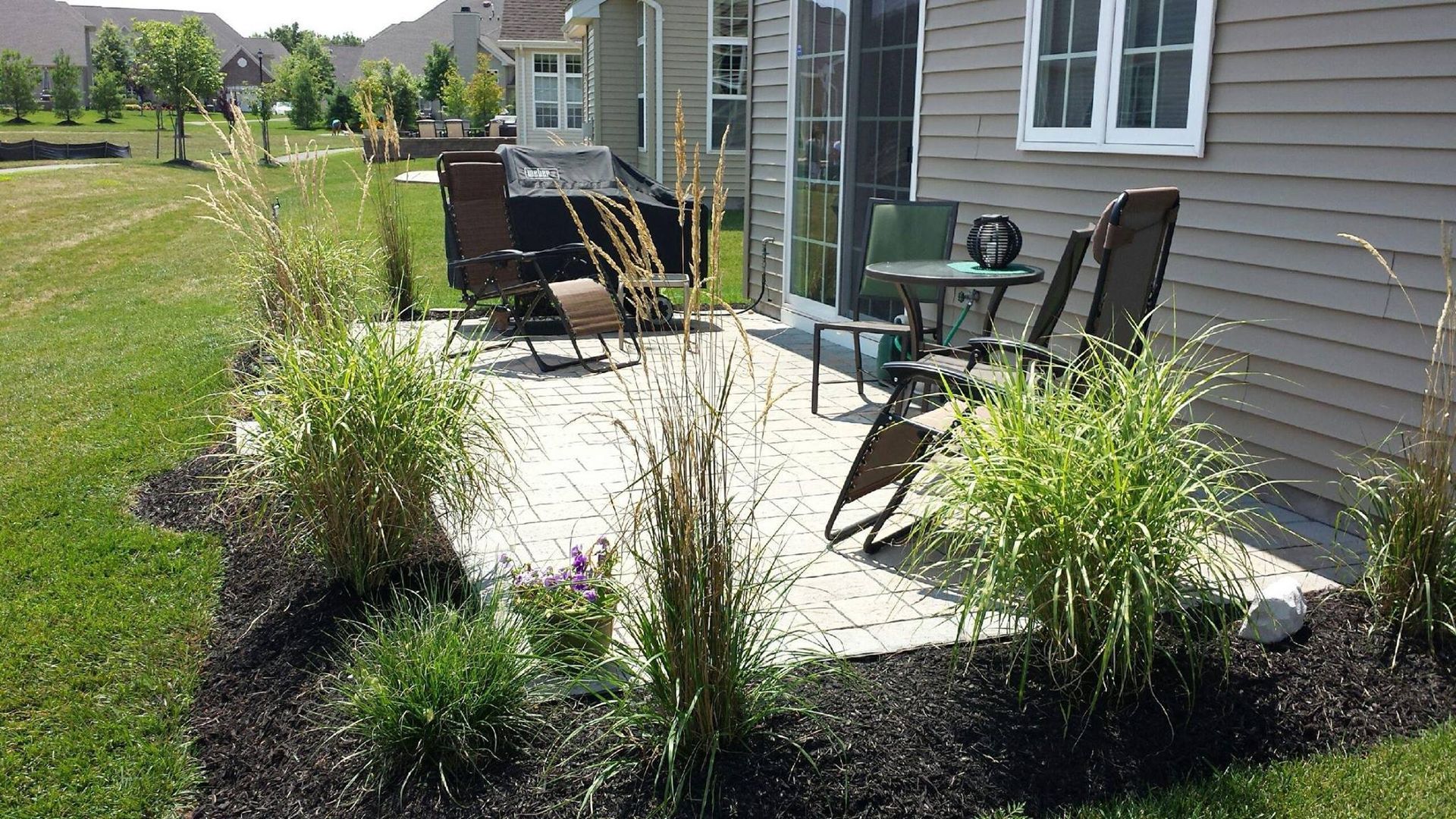 A patio with rocking chairs and a table in front of a house.