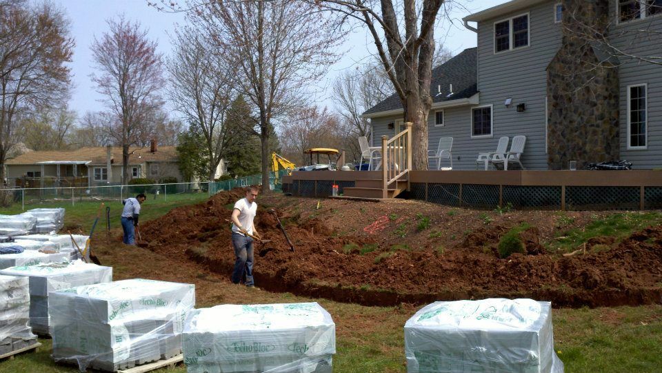 A man is digging in the dirt in front of a house.