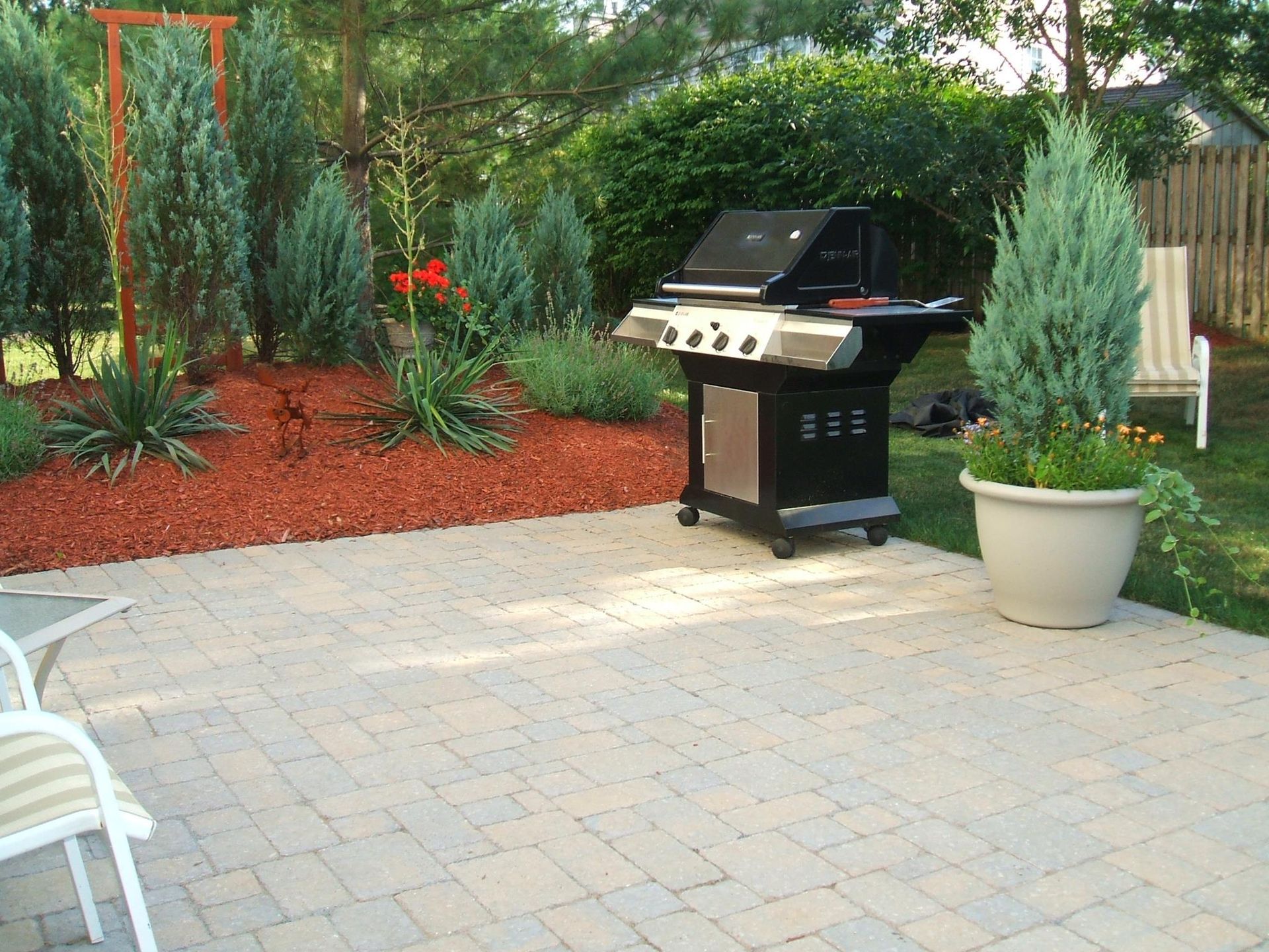 A grill is sitting on a patio next to a potted plant